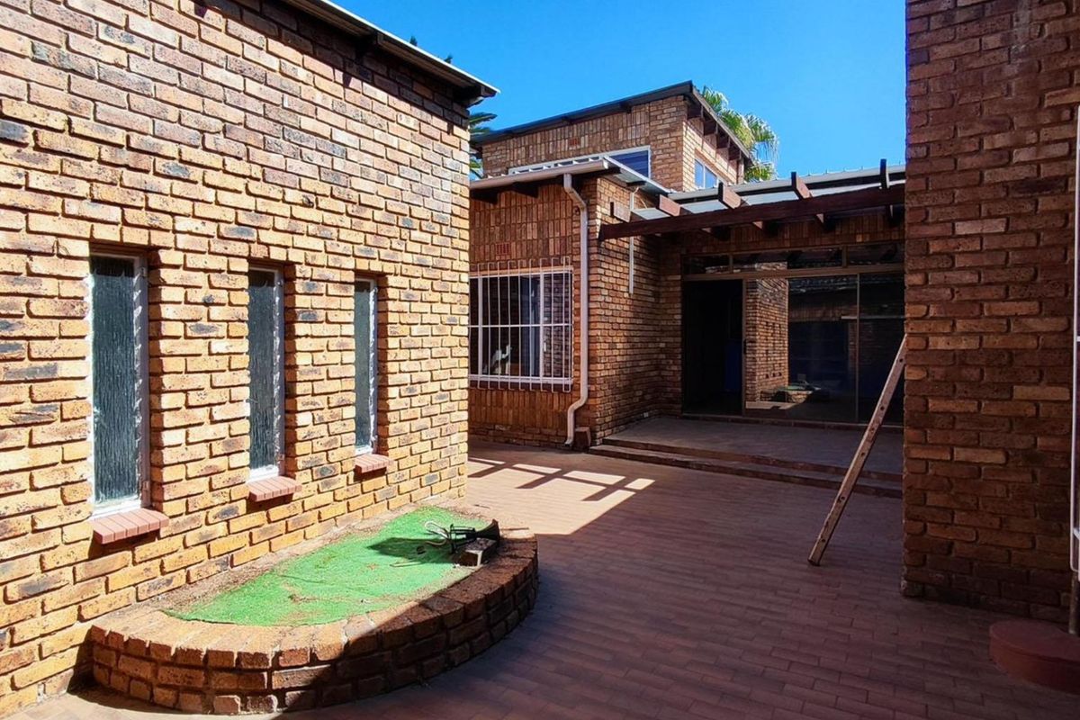 A private rear courtyard featuring face brick construction, a paved patio area, and a timber pergola structure.