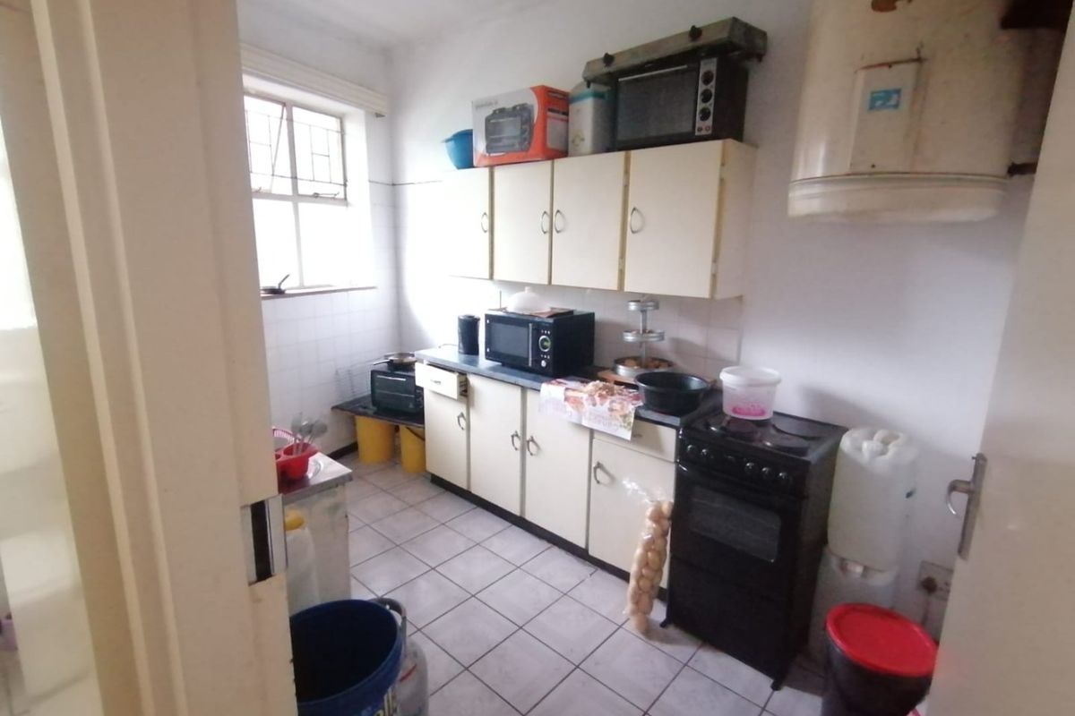 A functional kitchen featuring tiled flooring, built-in cabinetry, and an electric stove. The space would benefit from cosmetic updates to modernize the finishes.
