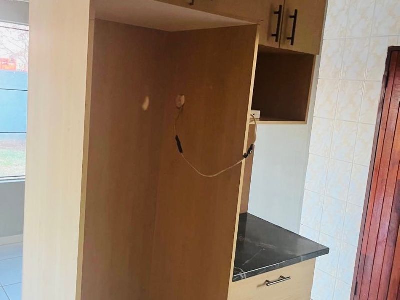 A kitchen area featuring built-in cabinetry and tiled finishes, currently requiring repairs to the ceiling and electrical fixtures.