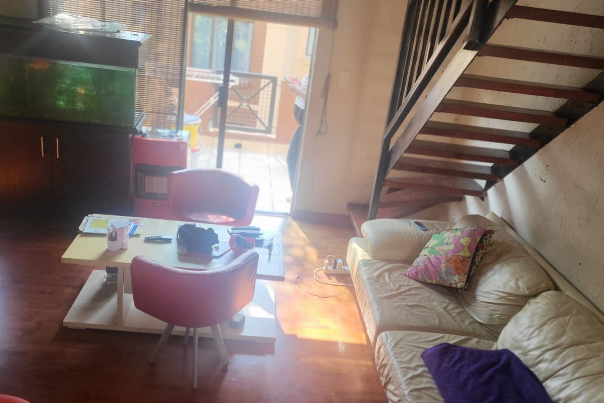 Living room area featuring laminate flooring, a wooden staircase, and access to an outdoor patio through a sliding glass door.