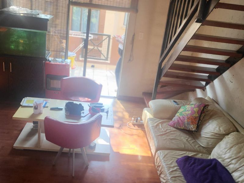 Living room area featuring laminate flooring, a wooden staircase, and access to an outdoor patio through a sliding glass door.