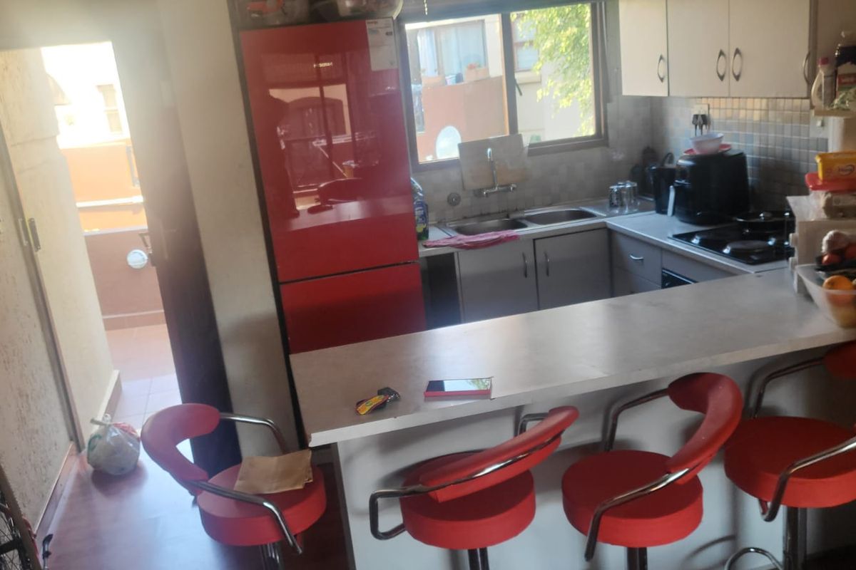 Compact kitchen featuring built-in cabinetry, a double sink, a hob, and a breakfast bar counter, with direct access to an outdoor balcony area.