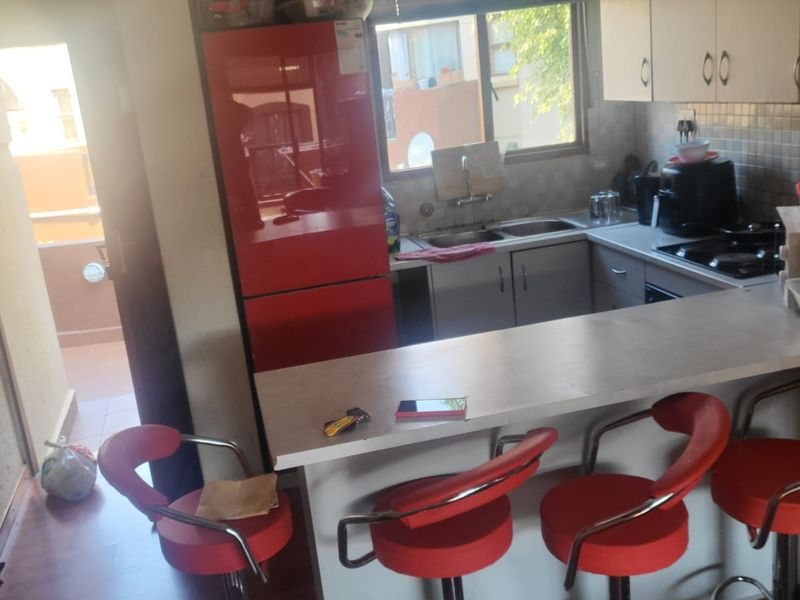 Compact kitchen featuring built-in cabinetry, a double sink, a hob, and a breakfast bar counter, with direct access to an outdoor balcony area.