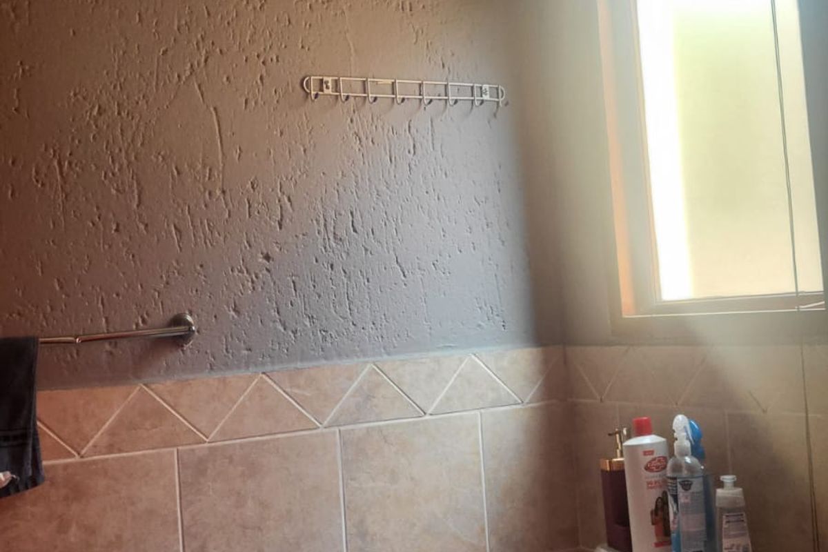 A compact bathroom featuring tiled walls, a standard toilet, and a window, offering a functional space with potential for cosmetic updates.