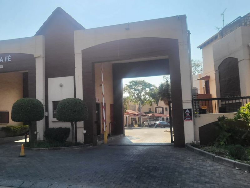The main entrance and security gatehouse of the Santa Fe residential complex, featuring a paved driveway and controlled access point.