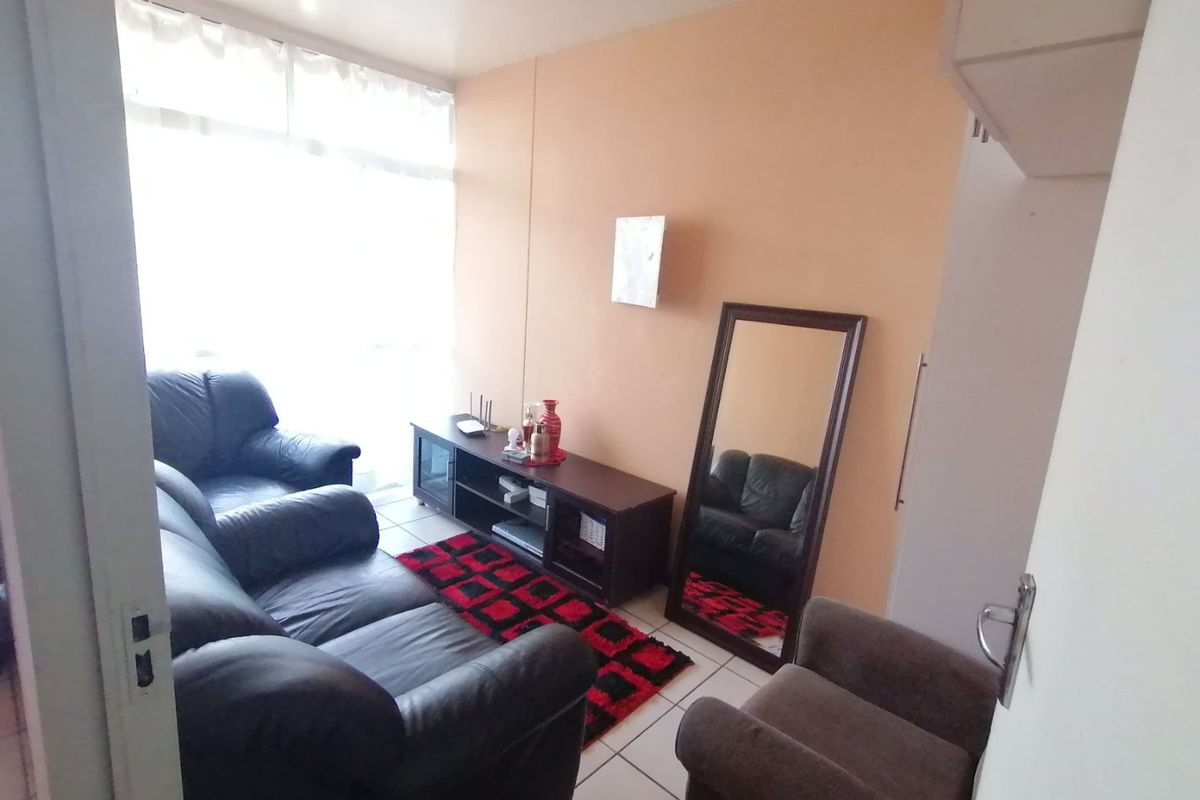 A compact living room featuring tiled flooring and a large window that provides natural light.