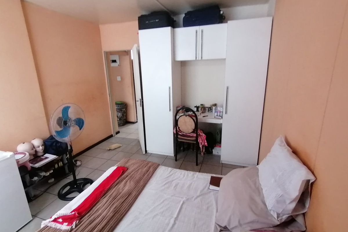 A bedroom featuring built-in white cabinetry and tiled flooring, requiring cosmetic updates to the wall finishes to improve the overall aesthetic.