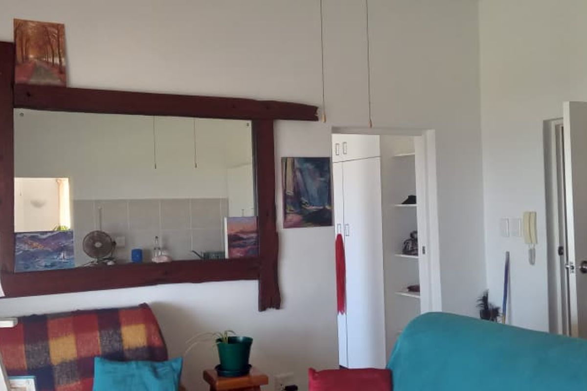 A living area featuring a timber-framed mirror, built-in storage cupboard, and an intercom system, providing a functional layout for the apartment.