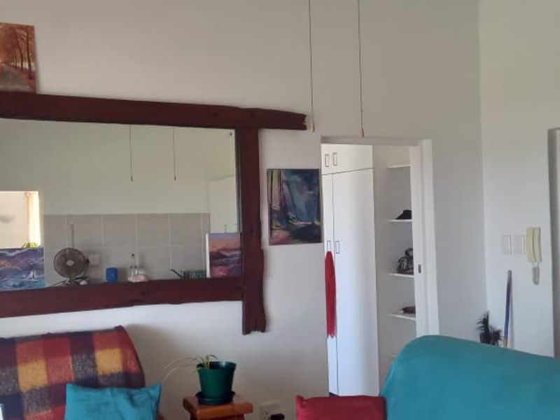 A living area featuring a timber-framed mirror, built-in storage cupboard, and an intercom system, providing a functional layout for the apartment.