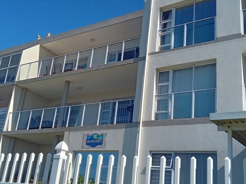 Exterior view of the Michaelpointe apartment building featuring multi-level balconies with glass balustrades and a secure picket fence perimeter.
