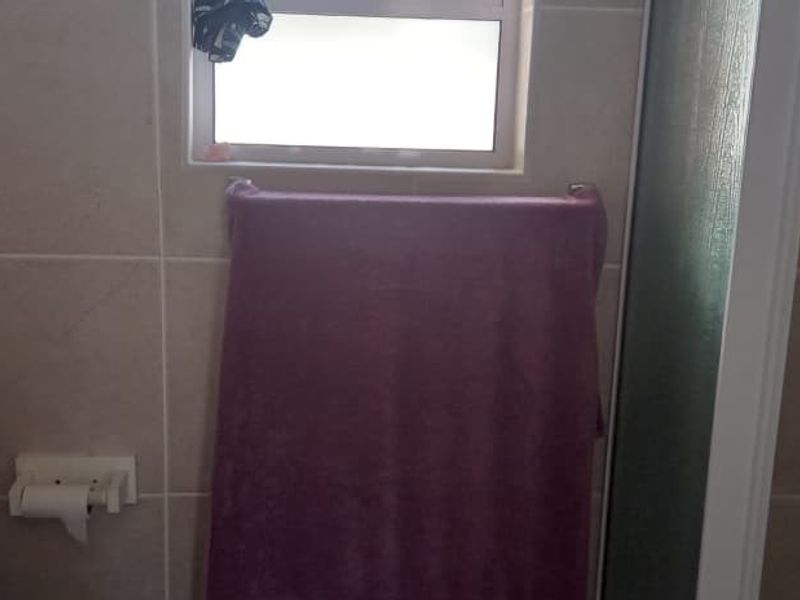 A functional bathroom featuring tiled walls, a shower enclosure, and a window for natural light.