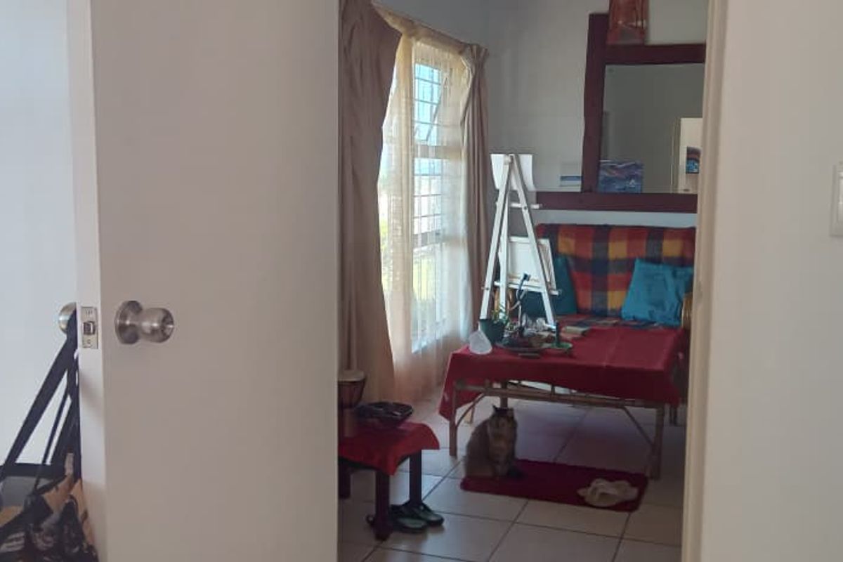 A bedroom featuring built-in cupboards and tiled flooring, viewed through a doorway.