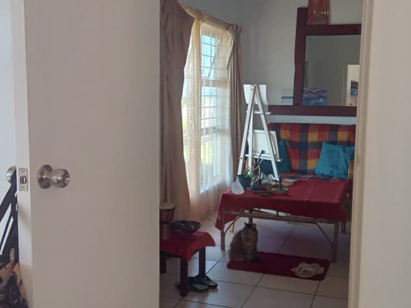 A bedroom featuring built-in cupboards and tiled flooring, viewed through a doorway.