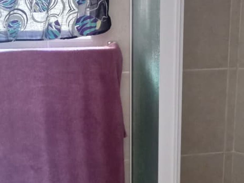A functional bathroom featuring a shower enclosure with tiled walls and flooring, providing a practical space for daily use.