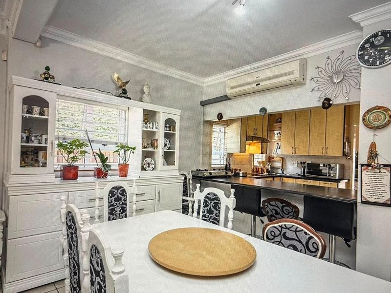 Open-plan kitchen and dining area featuring built-in cabinetry, a breakfast bar, and a split-system air conditioner.