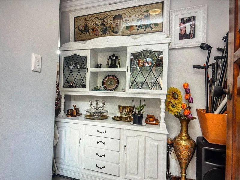 A view of a white built-in cabinet with glass-paneled doors and drawers, featuring decorative crown molding above.