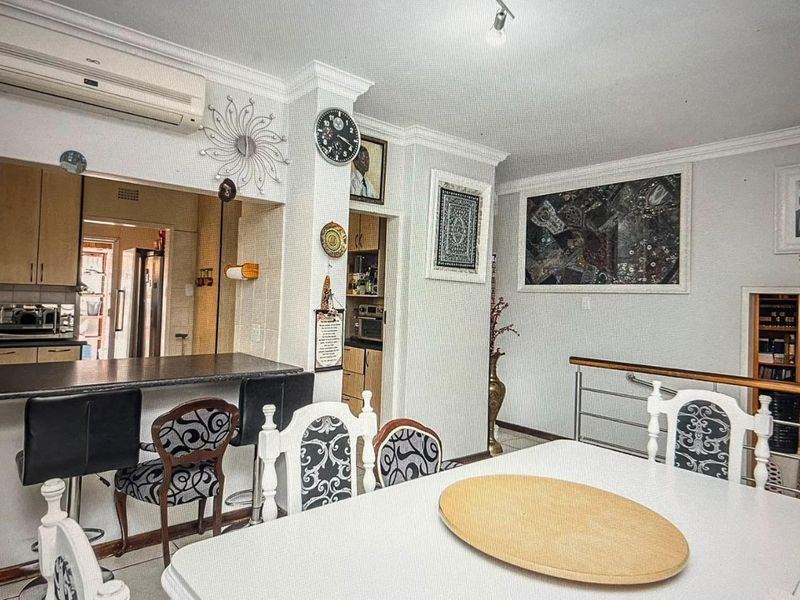 Open plan dining area featuring a breakfast bar, split system air conditioning, and direct access to the kitchen and staircase.