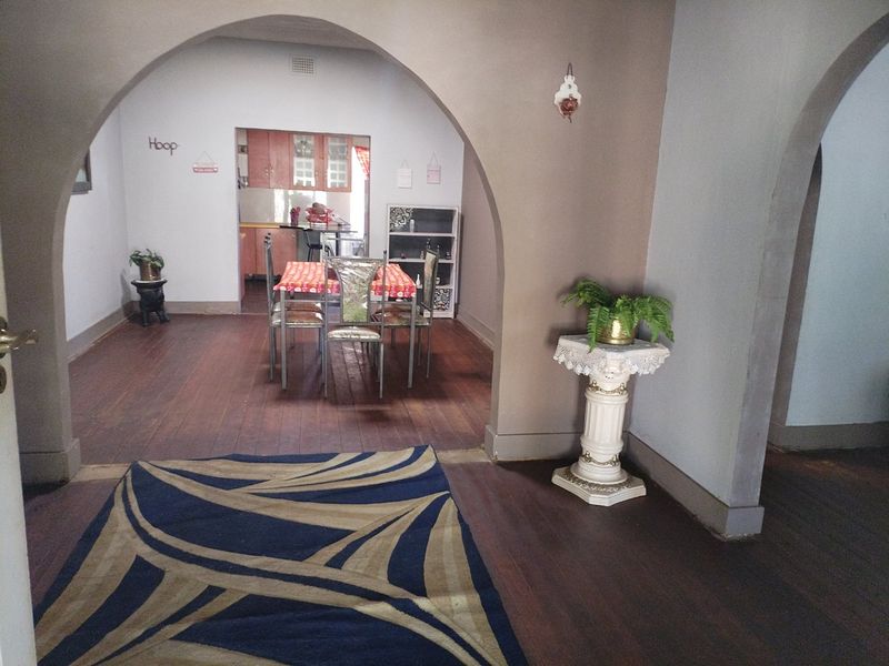 Open plan living and dining area featuring classic archways, hardwood flooring, and a view through to the kitchen space.