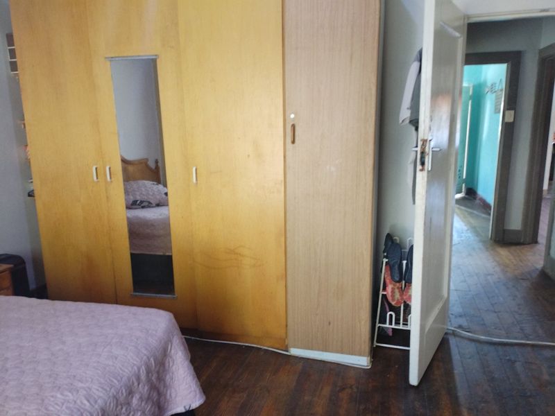 Bedroom featuring built-in wooden wardrobes and original timber flooring, offering a functional space with potential for cosmetic updates.