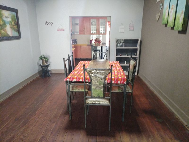 Dining room featuring original hardwood flooring with an open-plan view into the adjacent kitchen area.