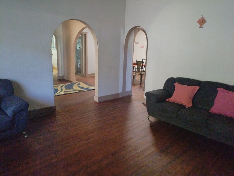 Living room featuring original hardwood flooring and distinctive arched doorways leading to adjacent living spaces.