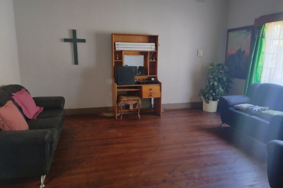 A living room featuring original timber flooring and neutral wall finishes, offering a blank canvas for potential interior updates and modernization.
