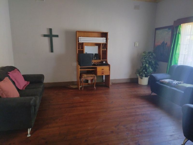 A living room featuring original timber flooring and neutral wall finishes, offering a blank canvas for potential interior updates and modernization.