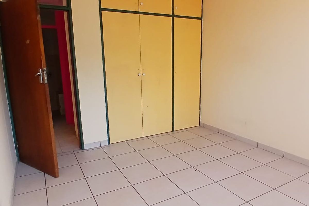 An empty bedroom featuring tiled flooring and built-in cupboards, offering a blank canvas for potential renovation or interior design updates.