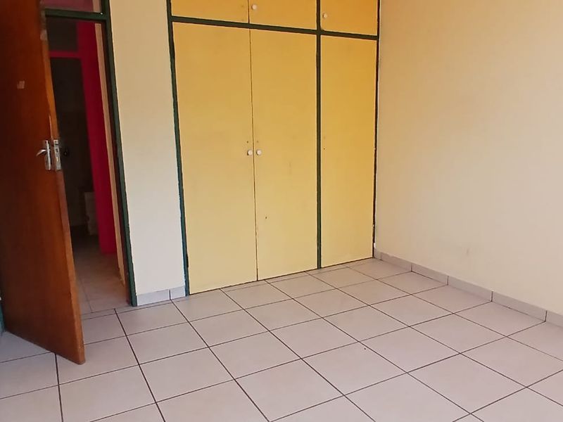 An empty bedroom featuring tiled flooring and built-in cupboards, offering a blank canvas for potential renovation or interior design updates.