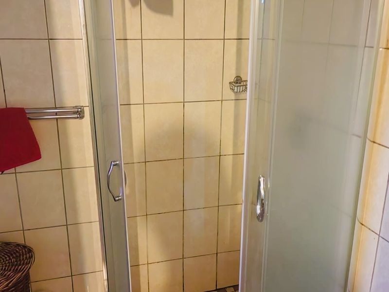 A functional bathroom shower area featuring a corner enclosure with tiled walls and flooring, requiring minor cosmetic updates to refresh the space.