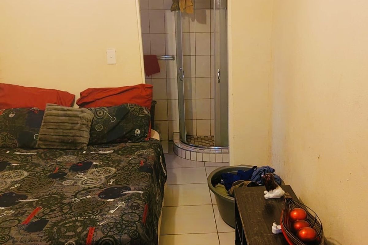 Bedroom featuring an en-suite bathroom with a shower cubicle, tiled flooring, and visible ceiling water damage requiring maintenance.