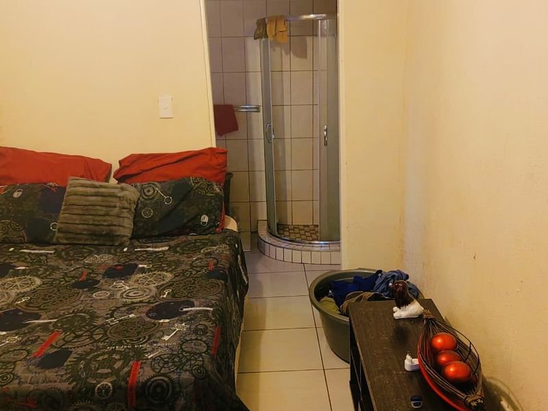 Bedroom featuring an en-suite bathroom with a shower cubicle, tiled flooring, and visible ceiling water damage requiring maintenance.
