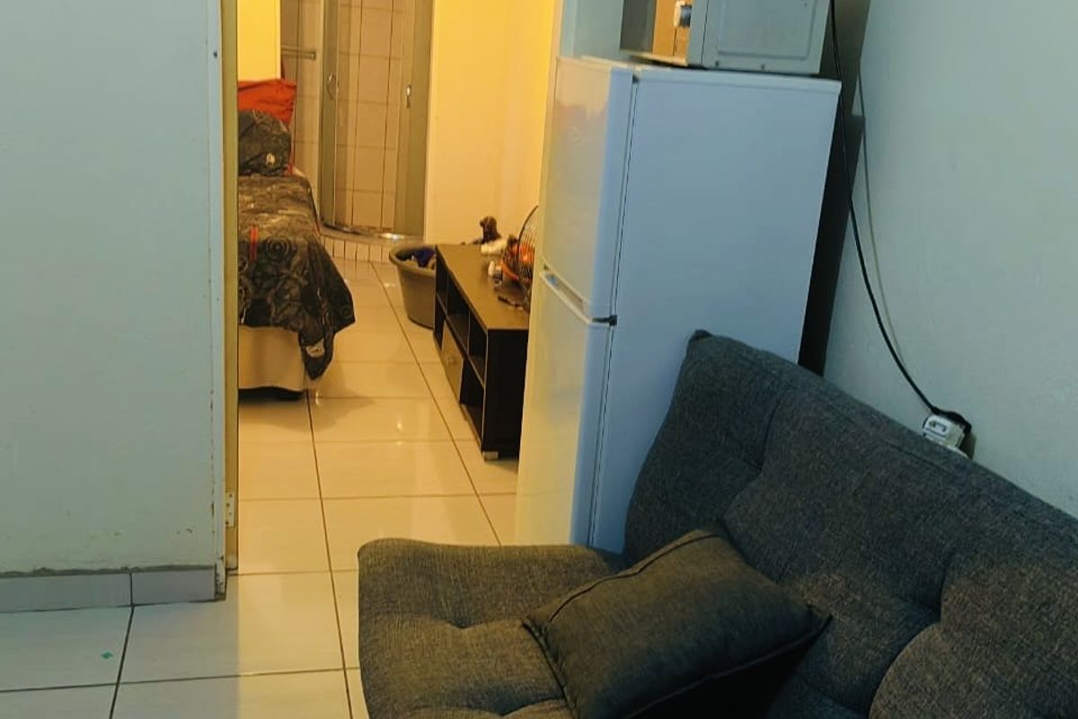 A view from a living area looking through a doorway into an adjacent bedroom and bathroom space with tiled flooring.