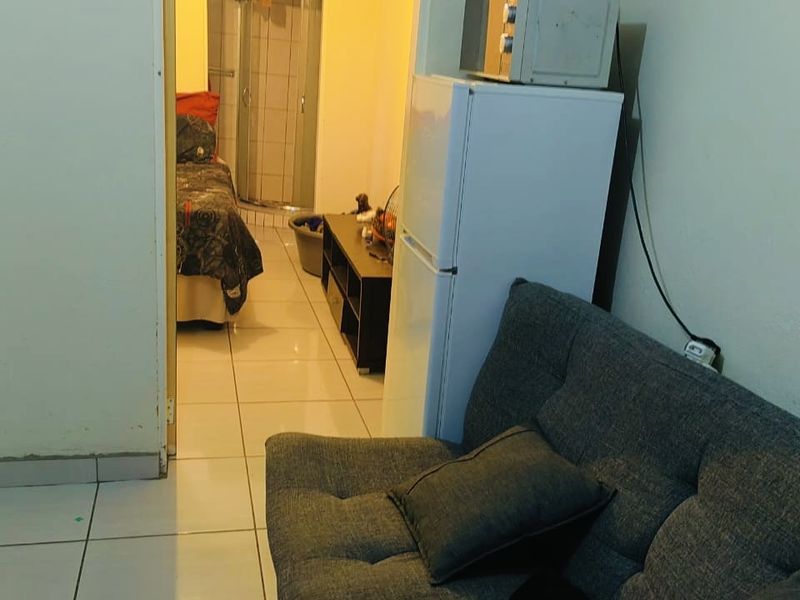A view from a living area looking through a doorway into an adjacent bedroom and bathroom space with tiled flooring.