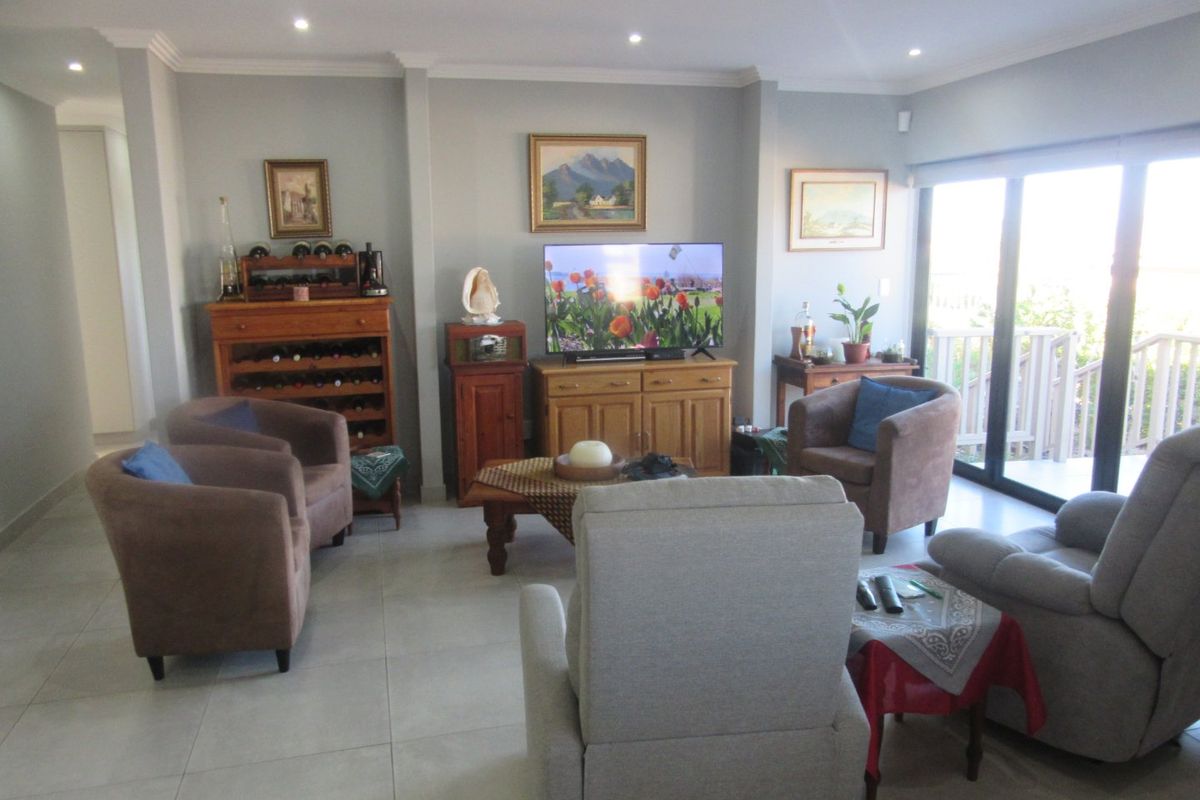 A comfortable living room featuring tiled flooring, recessed downlighting, and large sliding glass doors that provide access to an outdoor area.
