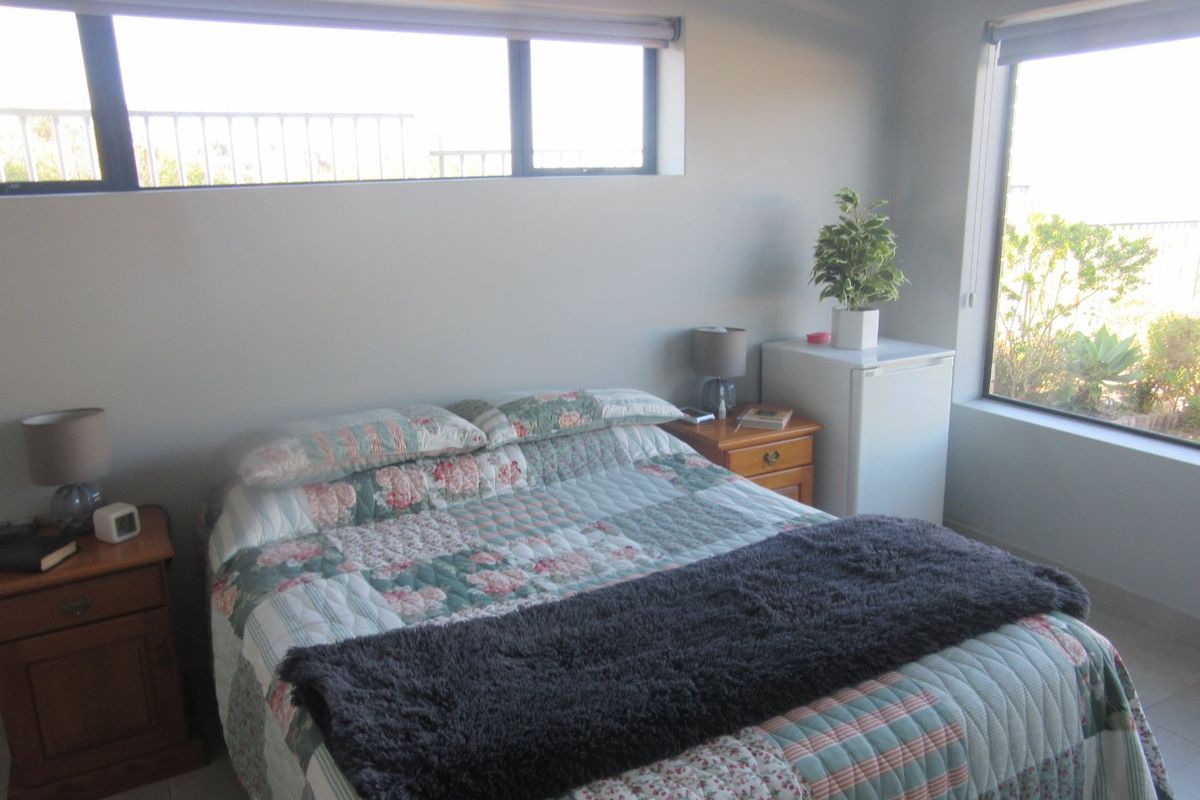A bedroom featuring tiled flooring and large windows that provide natural light and exterior views.