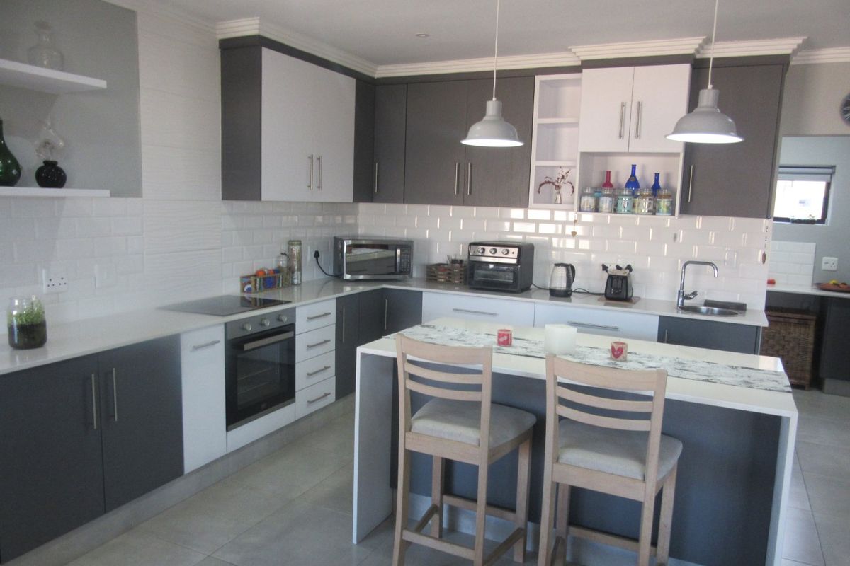 Modern kitchen featuring two-tone cabinetry, subway tile backsplash, quartz countertops, a central island, and integrated appliances.