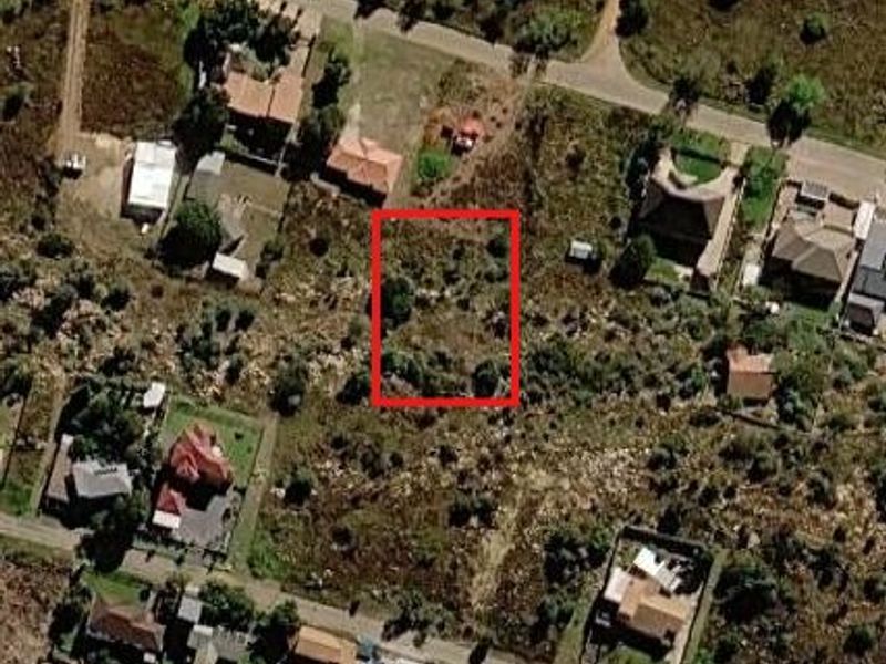 An aerial view of a vacant residential plot highlighted in red, situated within an established neighborhood.