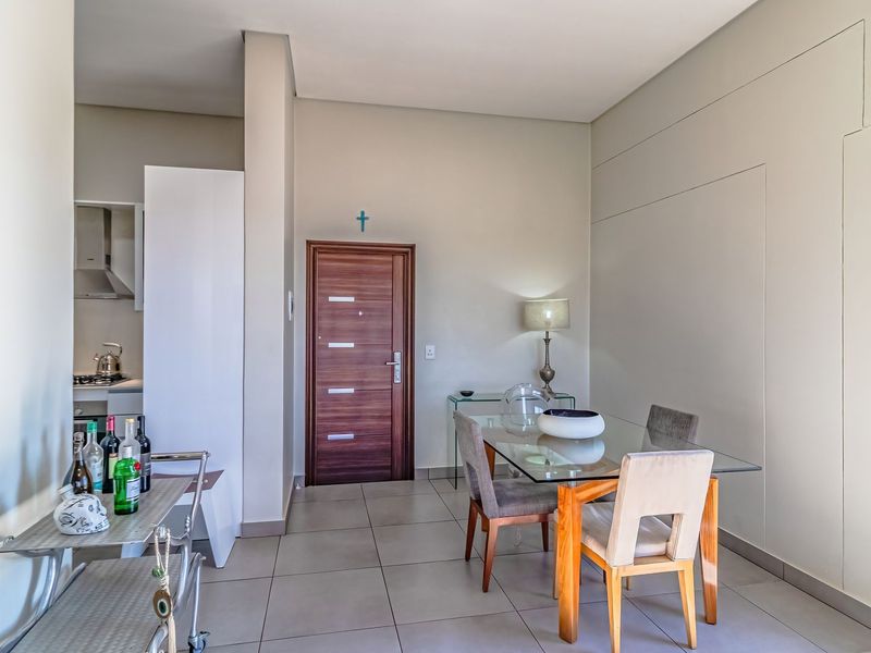 Open plan living and dining area featuring neutral tiled flooring, modern finishes, and direct access to a compact kitchen space.