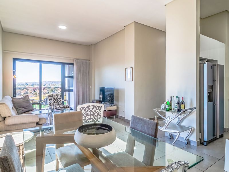 Spacious open-plan living and dining area featuring modern tiled floors, recessed lighting, and a sleek kitchen with integrated appliances and balcony access.
