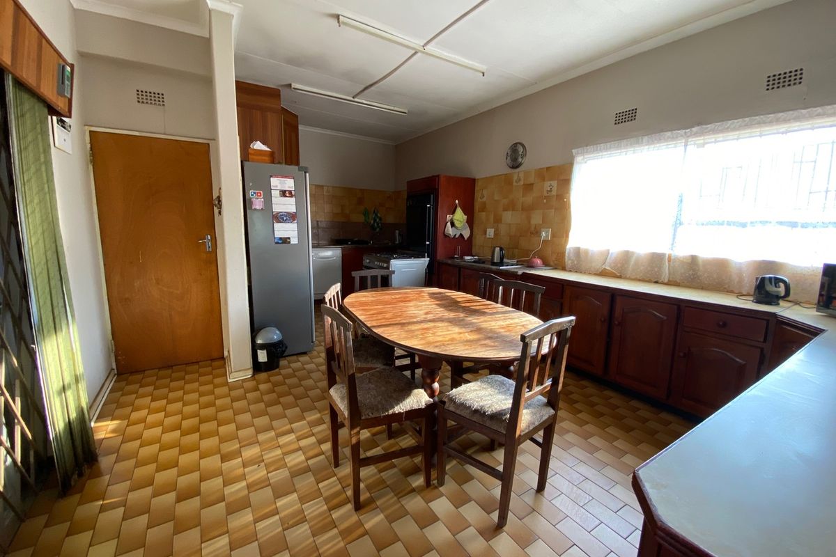 A dated kitchen featuring wooden cabinetry, tiled backsplash, and tiled flooring, offering a functional layout with potential for modern renovation.