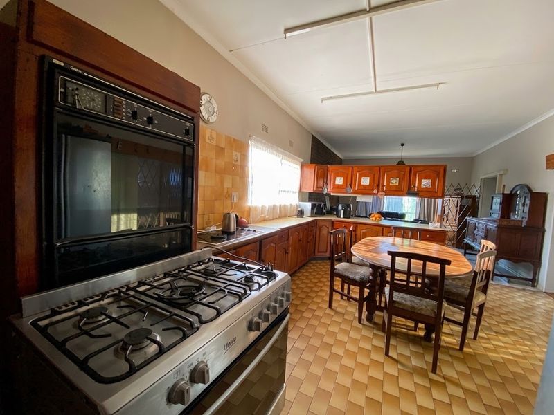 Spacious kitchen featuring traditional wooden cabinetry, a built-in oven, gas cooktop, and tiled flooring, offering a functional layout with potential for modern updates.