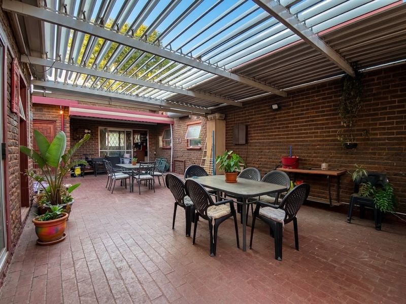 Spacious outdoor patio area featuring a louvred roof system, exposed brick walls, and durable brick paving, ideal for covered outdoor entertaining.