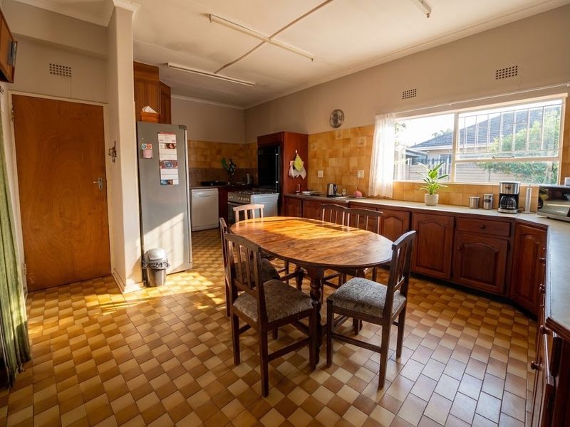 A dated kitchen featuring wooden cabinetry, tiled backsplash, and tiled flooring, offering a functional layout with potential for modern renovation.