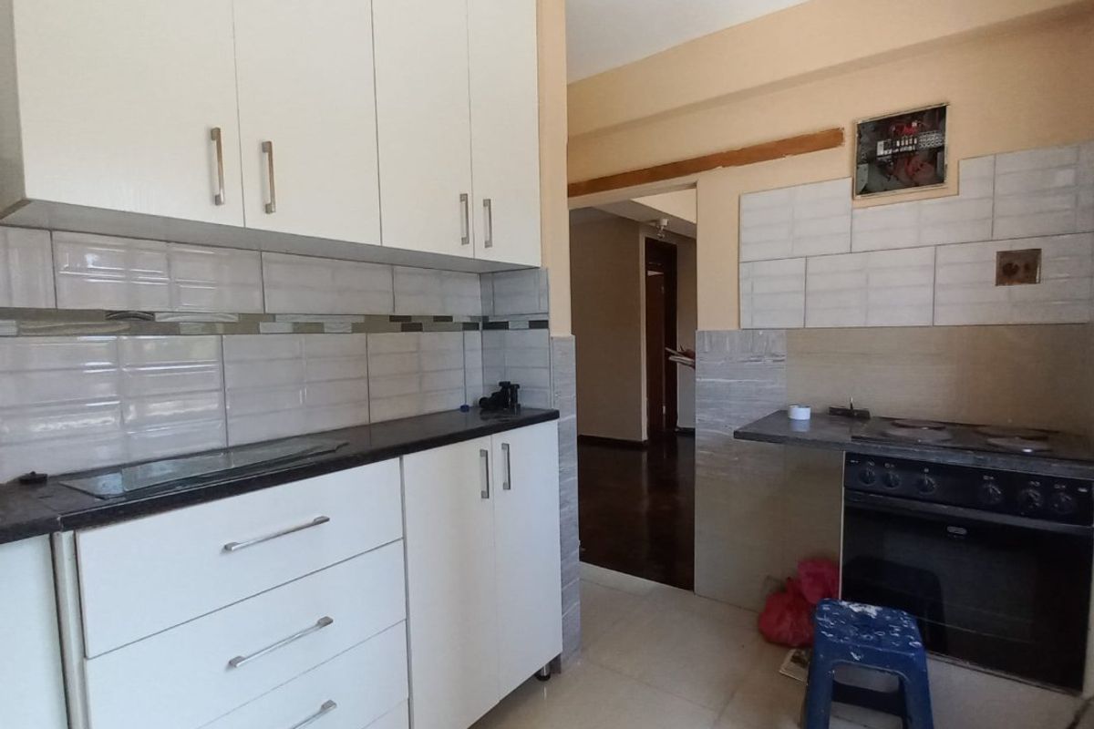 Kitchen featuring white built-in cabinetry, tiled backsplash, and integrated oven with hob. The space requires finishing touches to the wall and trim.