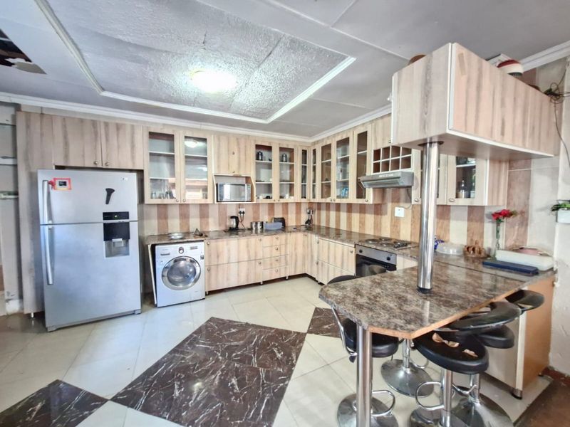 Kitchen featuring laminate cabinetry, granite countertops, breakfast bar, and built-in appliances, requiring ceiling repairs.