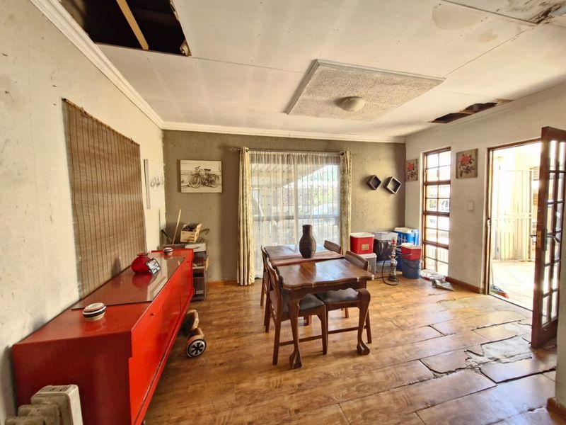 Dining area featuring tiled flooring and access to an outdoor space, currently requiring significant ceiling and flooring repairs.
