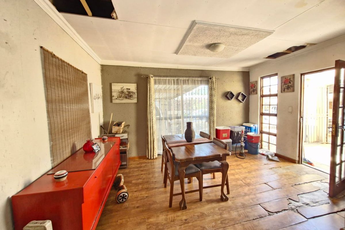 Living area featuring timber flooring and access to an outdoor space, currently requiring significant ceiling and flooring repairs.