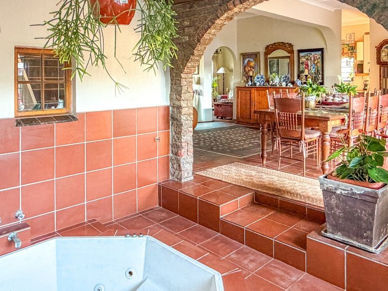 A unique bathroom area featuring a built-in corner bathtub, terracotta tiling, and a distinctive exposed brick archway leading into the adjacent living space.