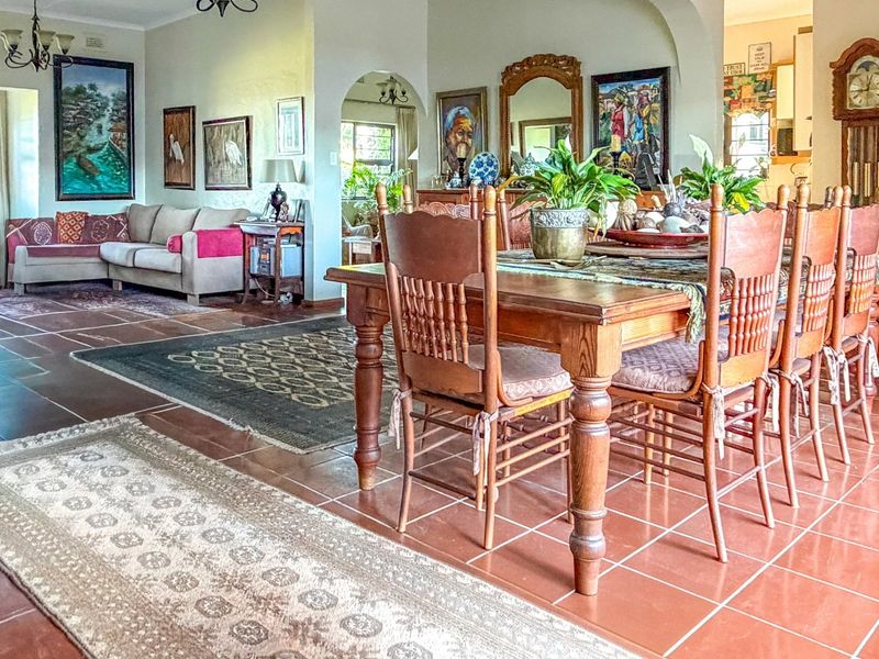Spacious open-plan living and dining area featuring traditional terracotta floor tiles, an exposed brick pillar, and classic arched architectural transitions.
